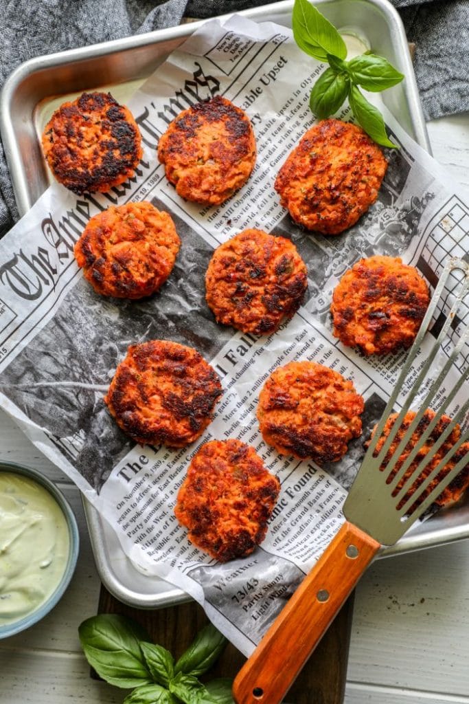 Cooked salmon cakes on paper on a tray.
