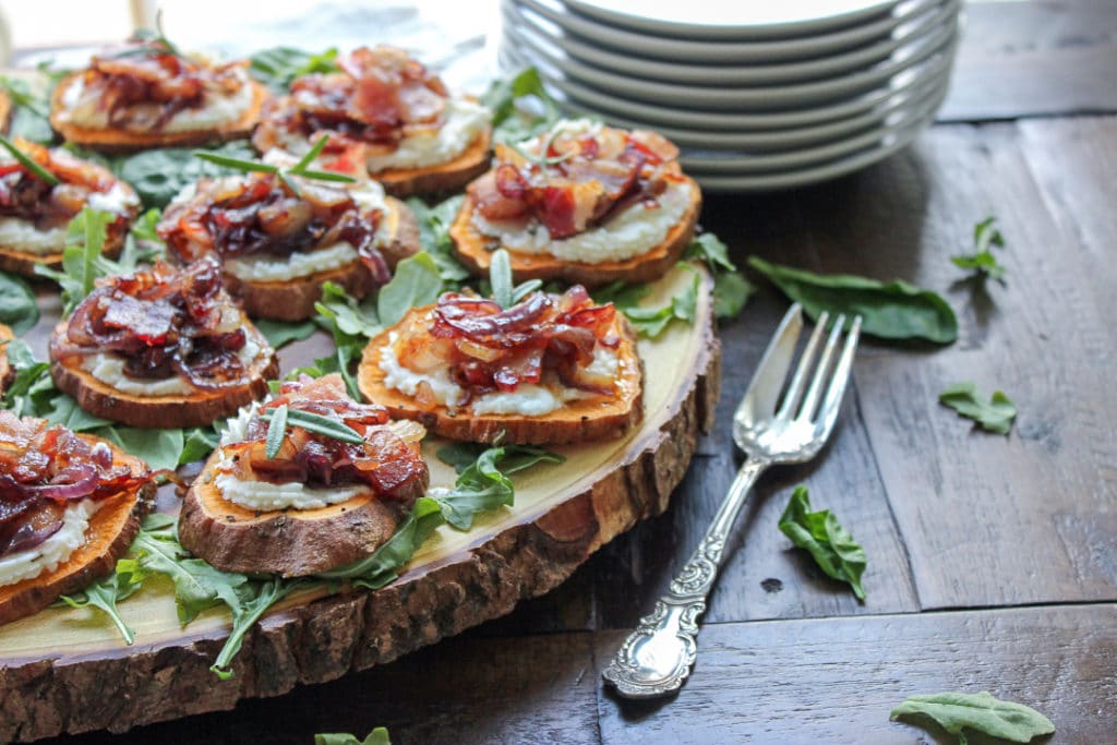 Sweet potato rounds on a wood turn table with a fork and plates in the background.
