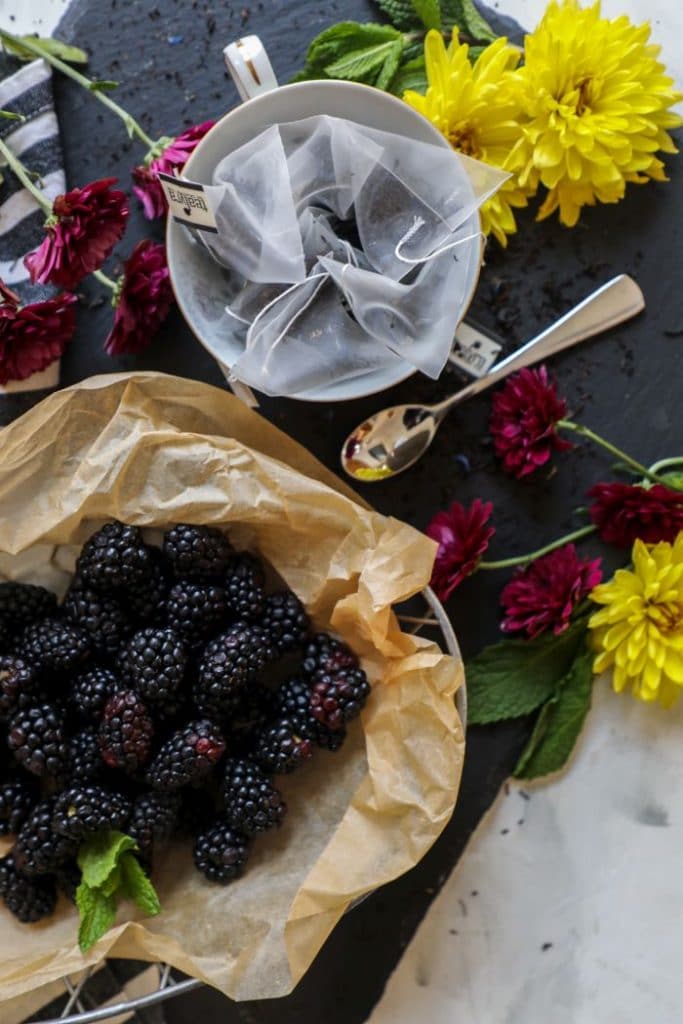 A close up of earl grey loose tea and fresh blackberries.
