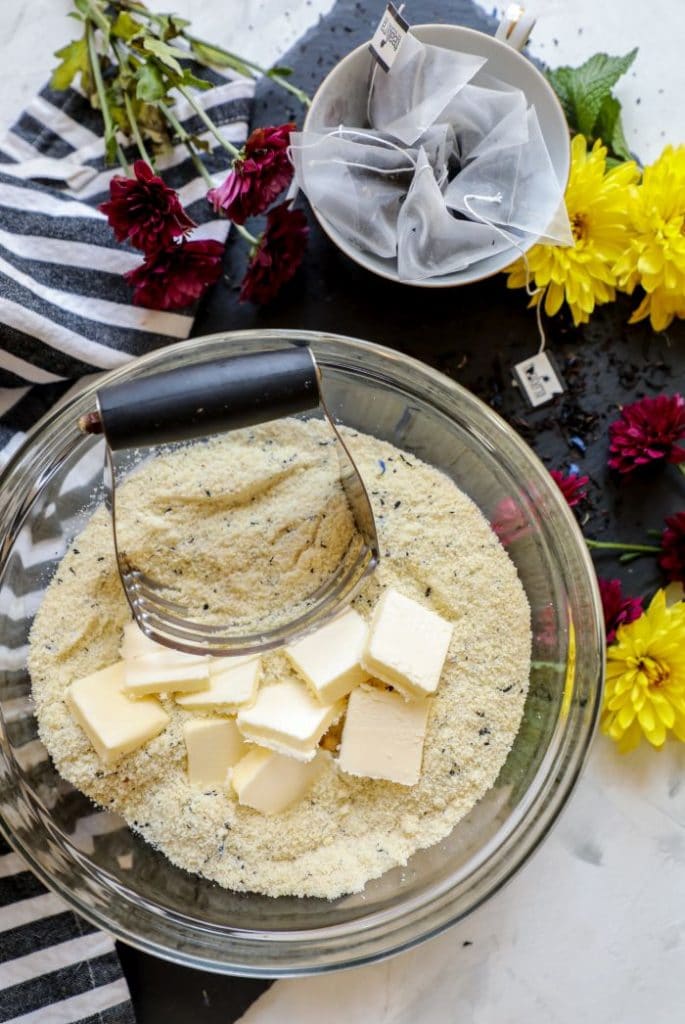 A bowl of dry almond flour and earl grey tea with cold butter in it in a bowl.