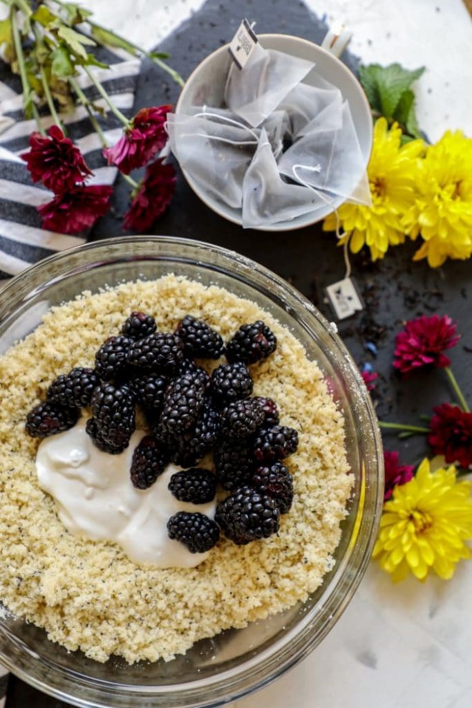 The bowl of dry ingredients with sour cream and fresh blackberries in it.