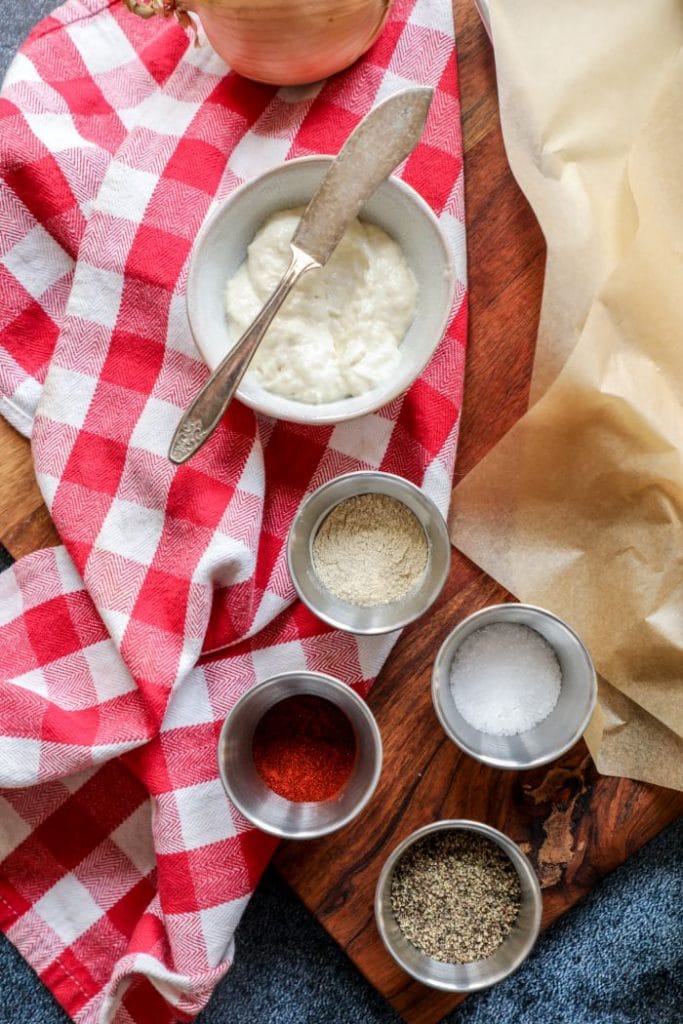 Spices and horseradish on a cutting board with a red towel.