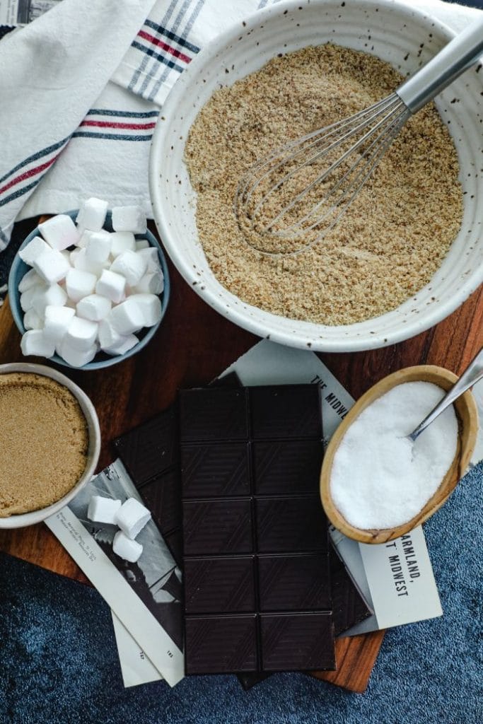 The ingredients placed on the table- toasted almond flour, keto marshmallows, and keto chocolate bars