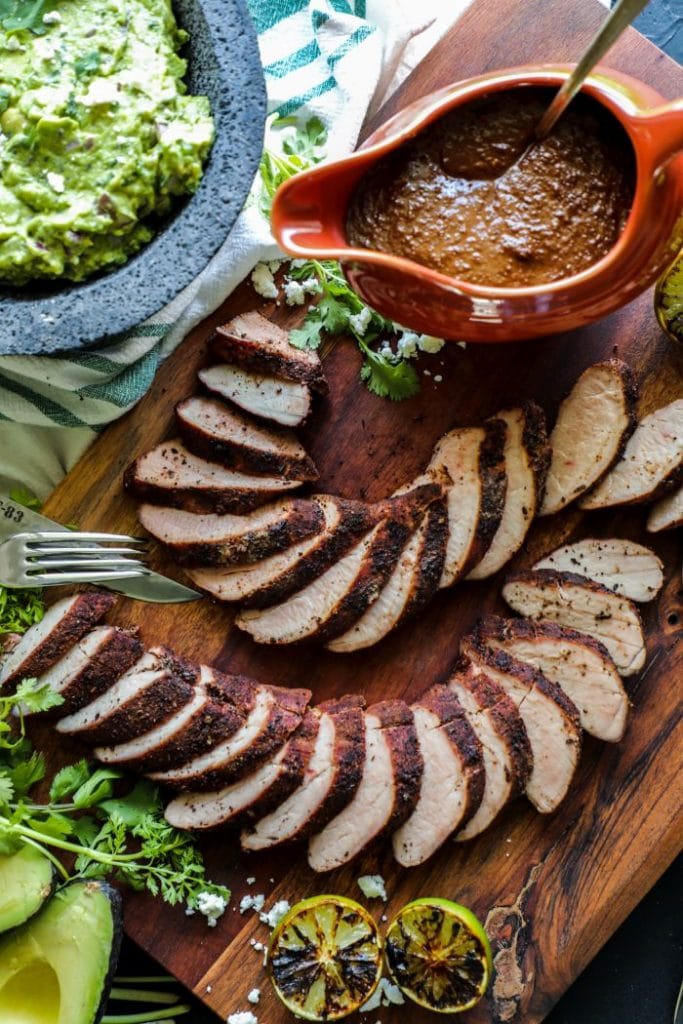 Freshly sliced medallion sized pork tenderloin fanned out on a cutting board.