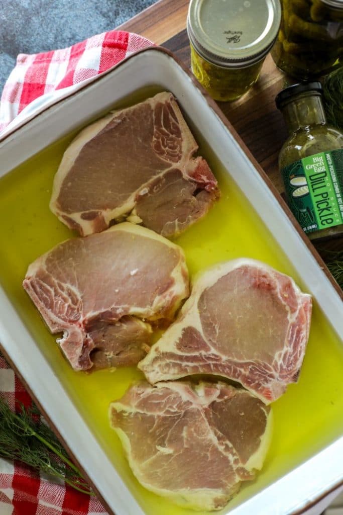 Smoked dill pickle pork chops in the pickle brine in a pan.