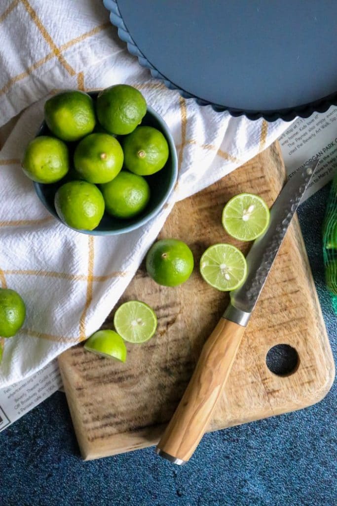 Key limes on a cutting board with a knife.