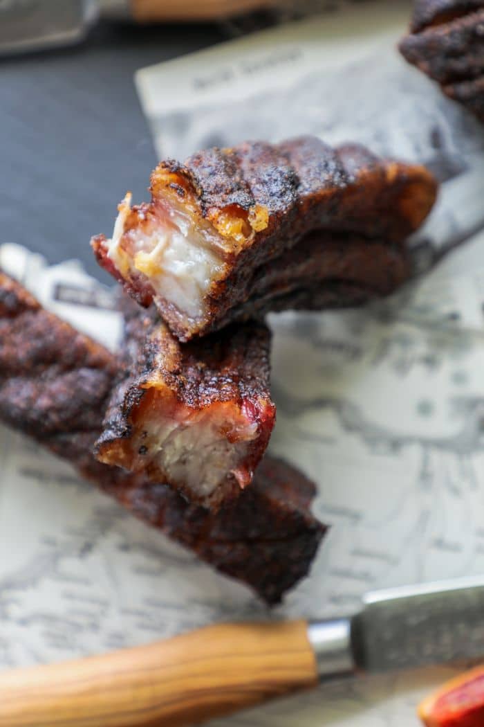 Hot and Fast Smoked Pork Belly sliced in half on paper with a knife.