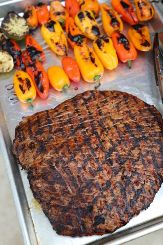 The adobo marinated flank steak cooked, and resting on a sheet pan.