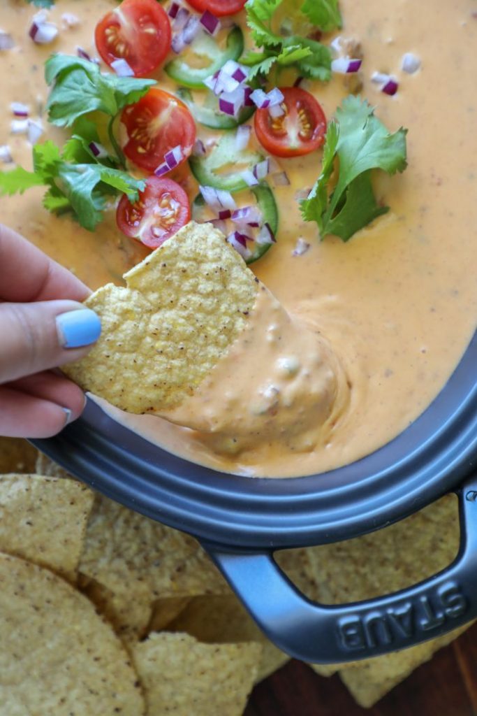 Chip being dipped into the smoked queso