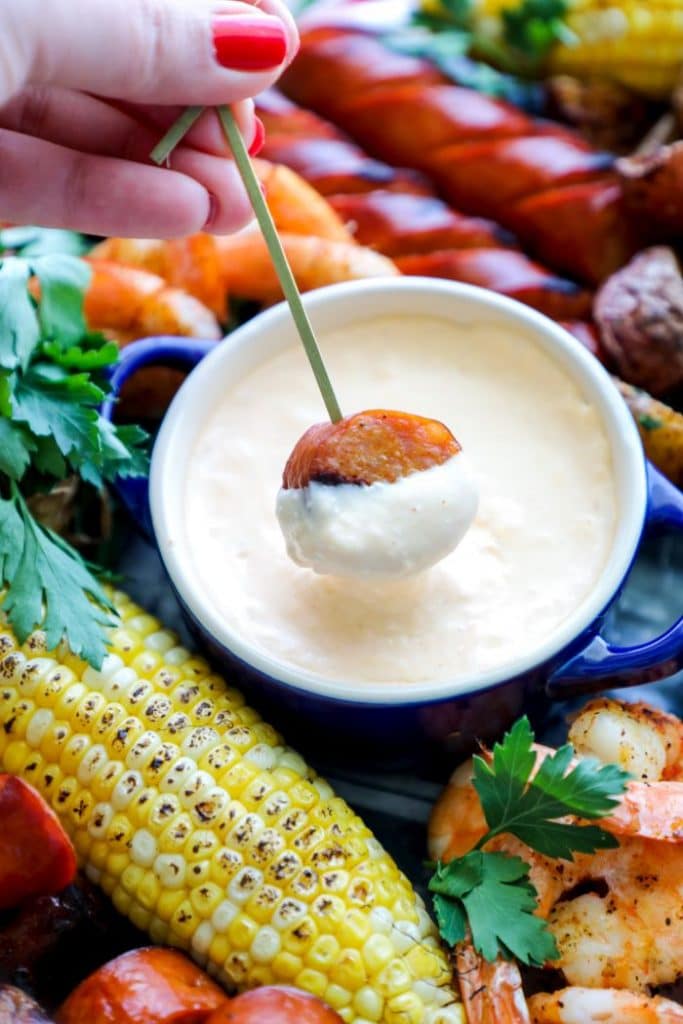 A sausage dipped into the beer cheese sauce