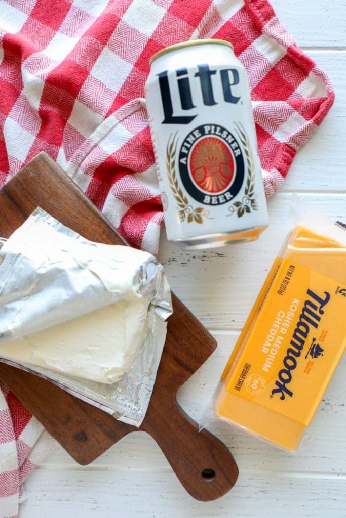 Beer cheese sauce ingredients on a white table with a red cloth
