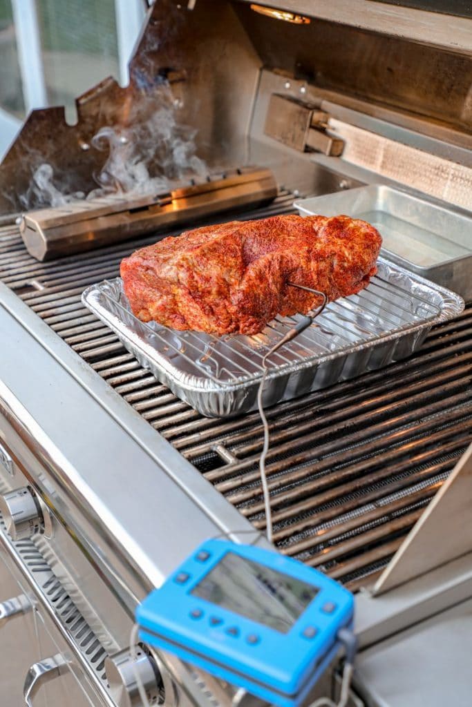 Pork butt being smoked on a gas grill