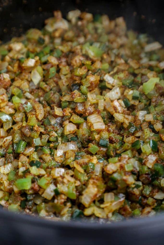 Cooked onions and peppers and chili seasoning in a dutch oven
