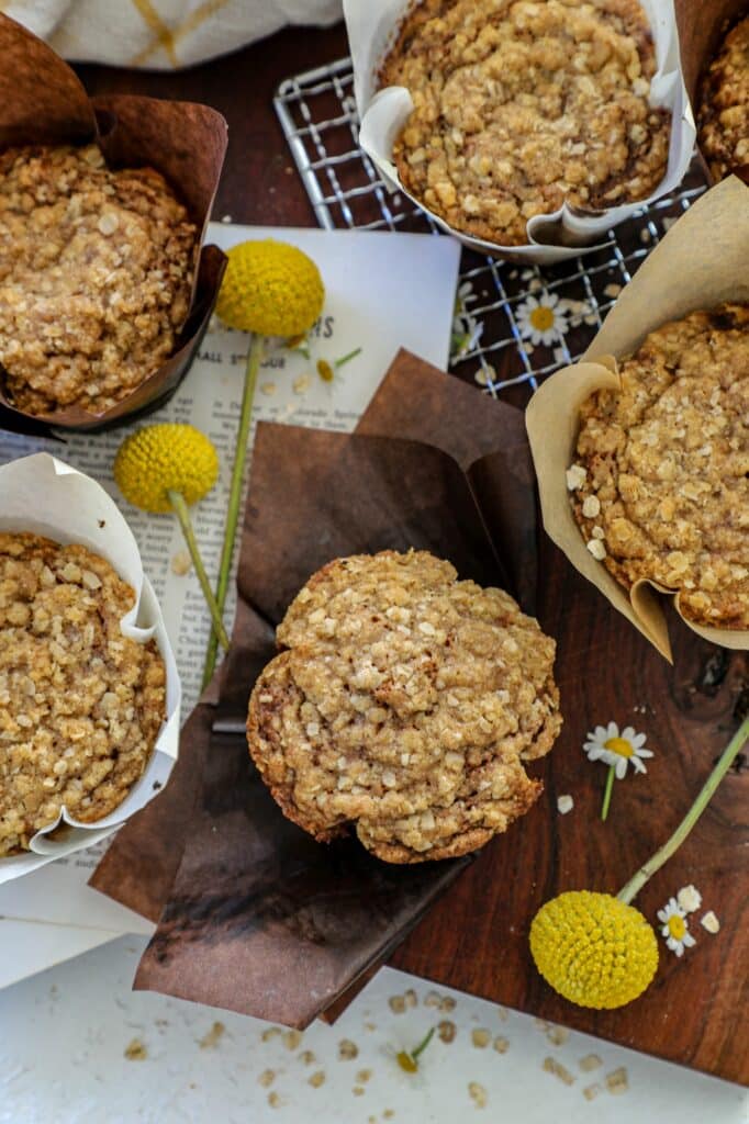 Banana oatmeal muffins wrapped in paper with cooling rack in background.