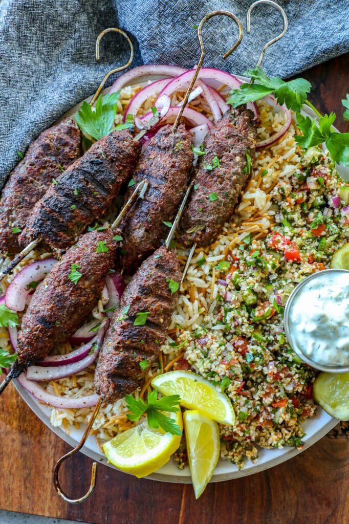 Kofta kebabs on a serving platter on top of rice pilaf and salad.