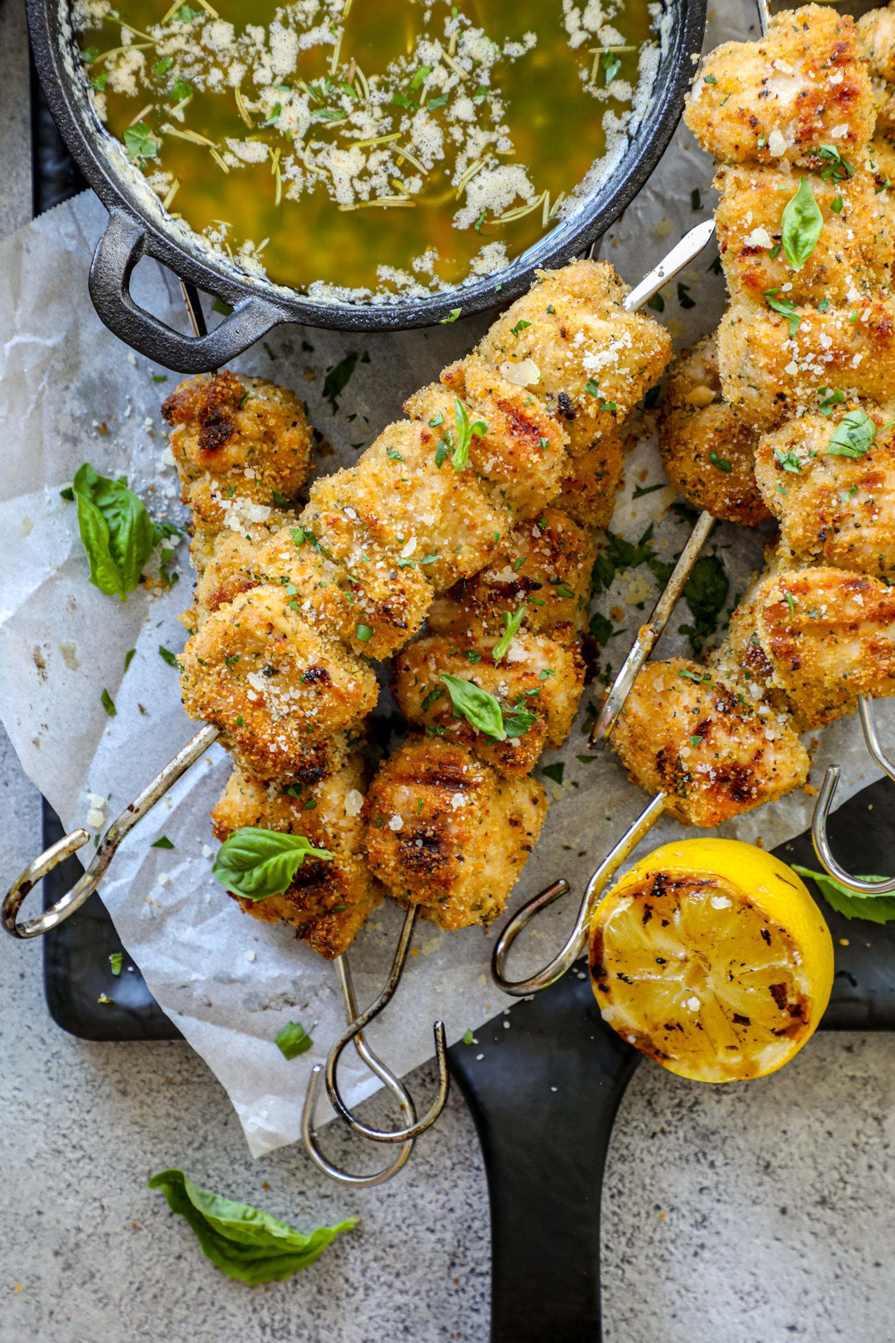 Grilled Chicken Spiedini skewers stacked on top of each other next to butter sauce.