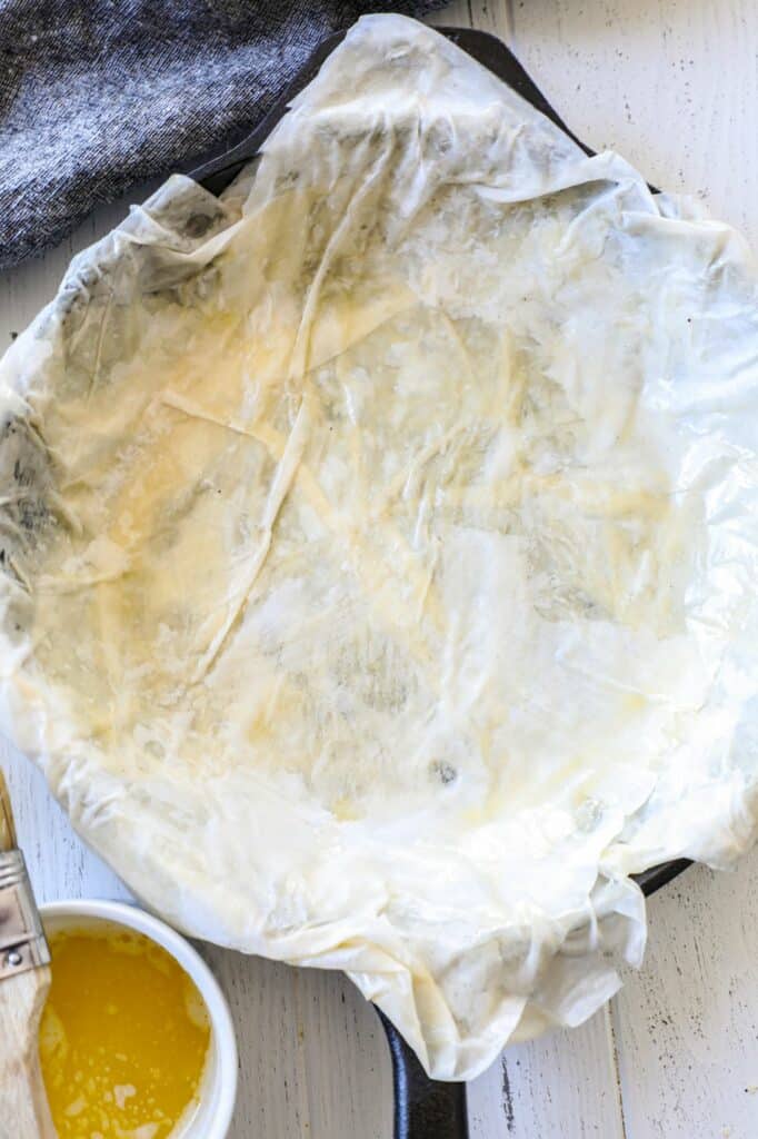 The first few layers of building a phyllo dough tart in a cast iron skillet