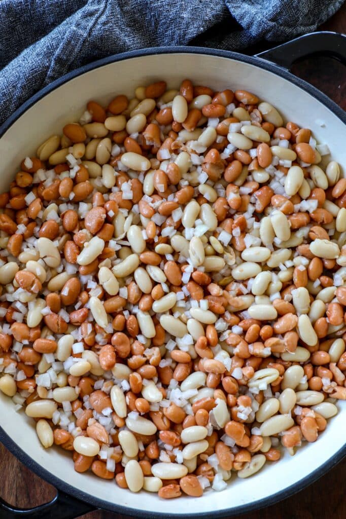 Adding the canned beans and diced onion to the pan