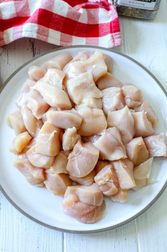 Chicken breast diced into cubes on a white plate.