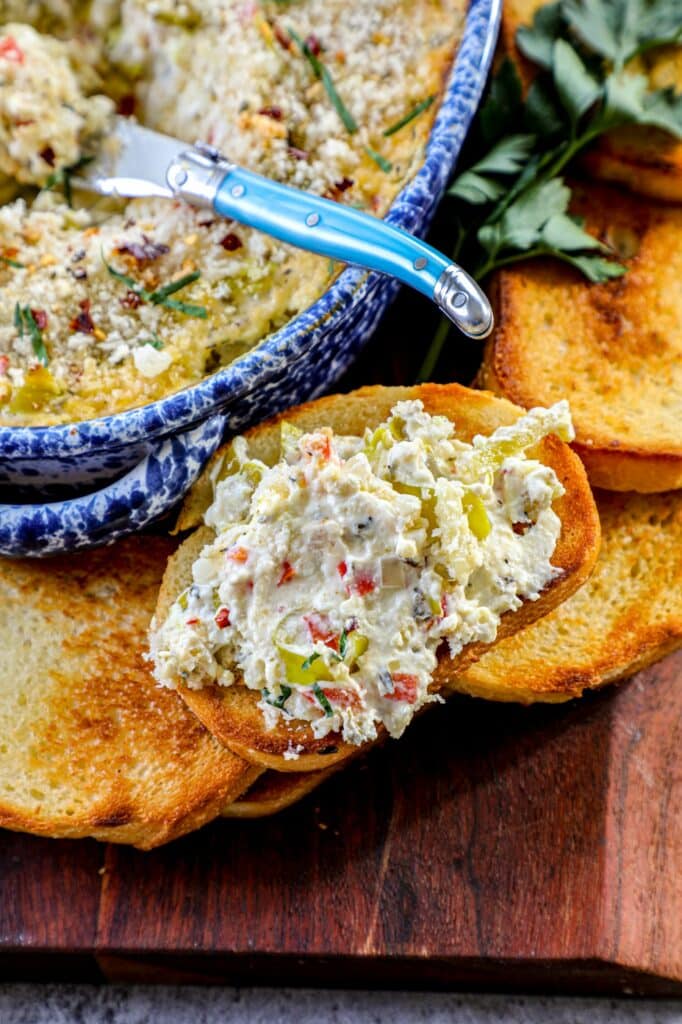 Pepperoncini Dip in a baking dish next to toasted bread with the dip on top.