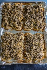 adding the cooked ground beef to the slider bun bottoms