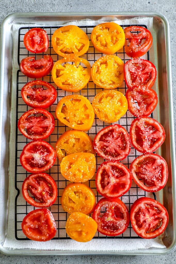 Sliced tomatoes salted and sitting on a baking sheet to remove excess moisture