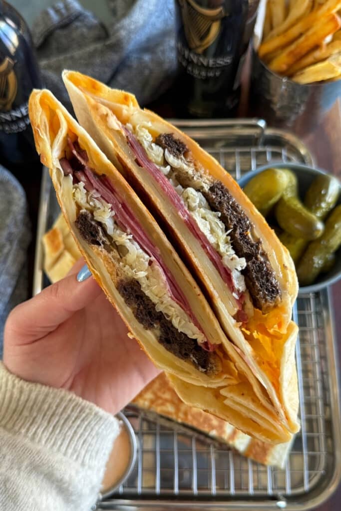 Holding a sliced in half Reuben Crunchwrap