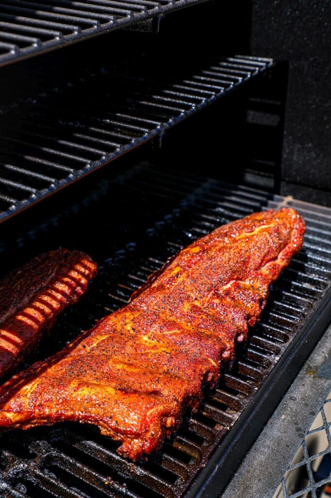 Prepped baby back ribs on the smoker grill grates