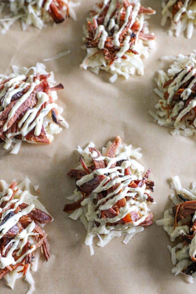 Prepping the shredded cheese and ham with the sauce on the baking sheet