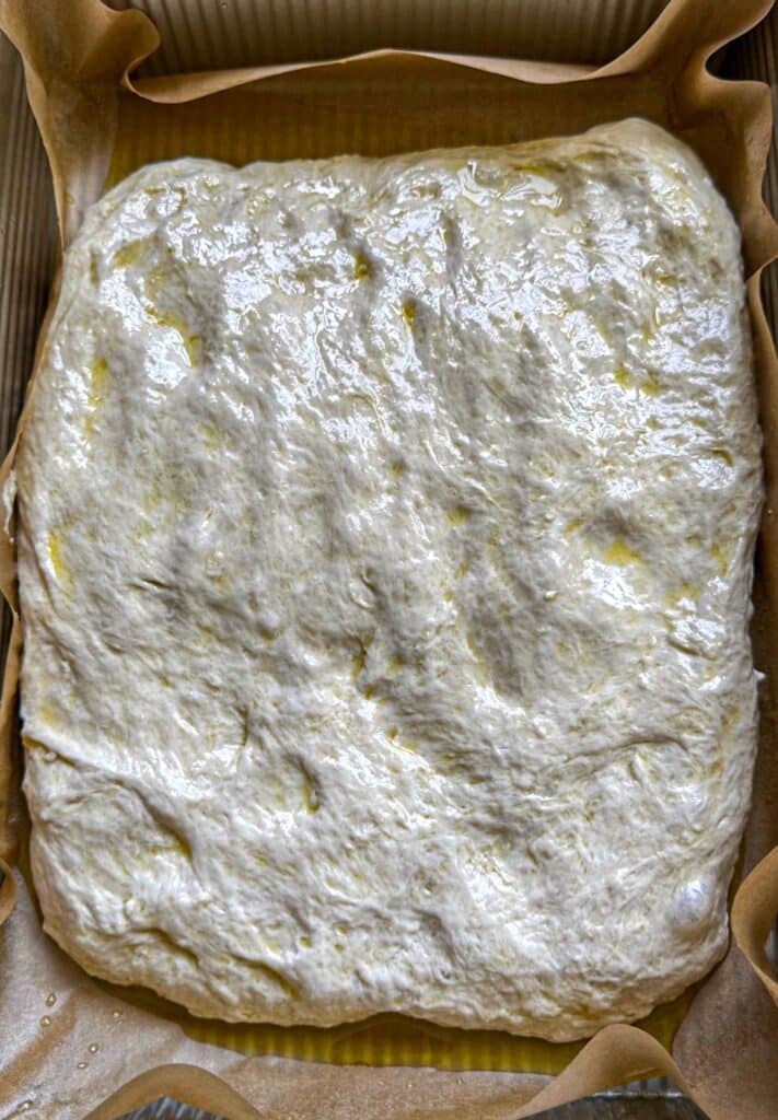 Focaccia dough pressed into the pan and fermenting