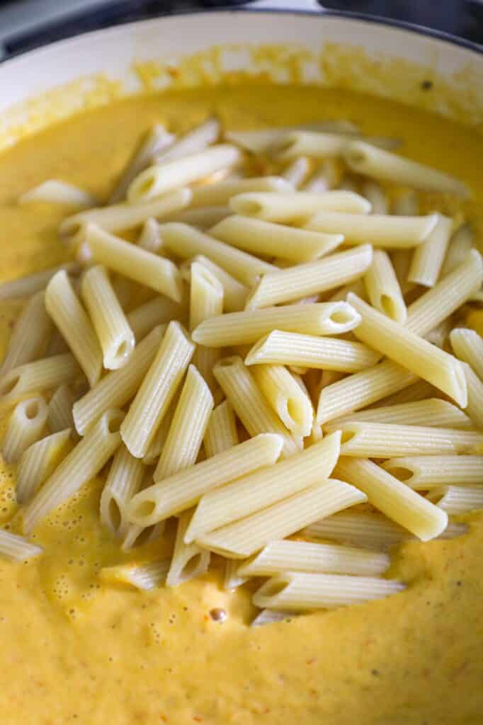 adding the pasta to the sauce back onto the stove