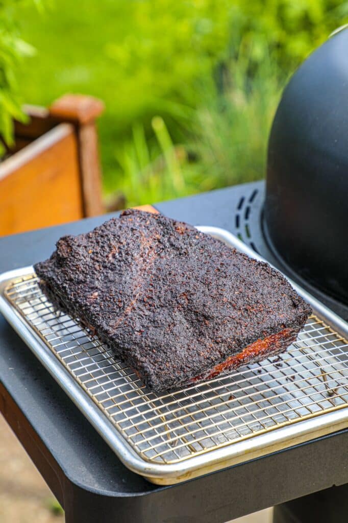 Pulling the smoked pork belly slab (brisket style) off the smoker